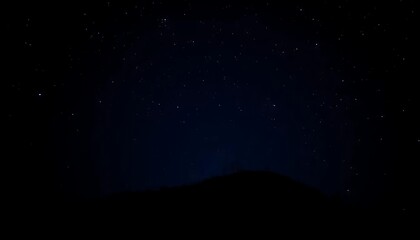Naklejka premium Astrophotography showing a dark silhouette mountain range under a starry night sky