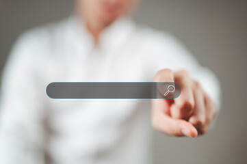 A man wearing a white shirt is pointing his index finger at the search button.
