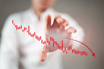 A businessman in a white shirt is holding a falling stock chart.