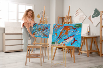 Female artist with paintings in workshop