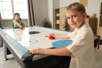 Little boy with girl playing air hockey at home