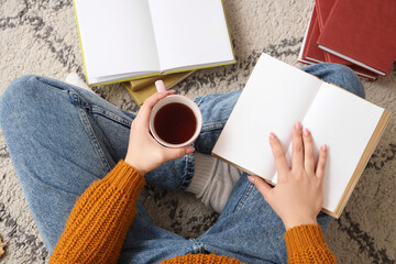 Obraz premium Cozy home reading with hot tea and open book on carpet, relaxing leisure activity and self-care moment