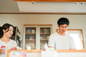 A Japanese couple in their 20s is preparing milk for their newborn in the kitchen. Their quiet teamwork and gentle care create a warm, intimate moment. Great for parenting or family-themed content.