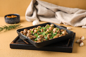 Baking dish with tasty mushrooms and green onion on beige background