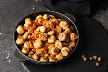 Frying pan with roasted mushrooms nd peppercorns on black background