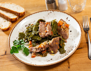 Braised beef tenderloin stew are complemented with vegetable stewed French green bean and carrot vegetable. Food styling, served lunch. Dish decorated with parsley leaf.