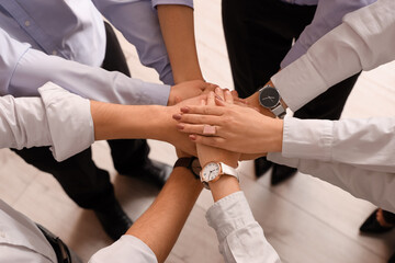 Business people putting hands together in office, top view