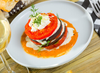 Healthy eating. Stack of fried eggplant with tomatoes, soft cheese and piquant sauce