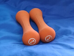 Two orange dumbbells on a blue tablecloth background.photo taken in malaysia
