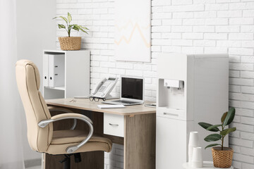 Interior of light office with modern water cooler and workspace