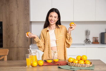 Obraz premium Young woman with fresh oranges and juice in kitchen