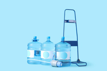 Trolley with bottles of clean water on blue background