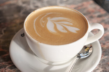 Warm latte with intricate foam design served in a cafe