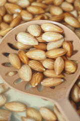 Almonds displayed in a wooden scoop on a textured surface
