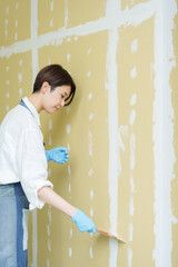 石膏ボードにパテを塗るDIYする女性