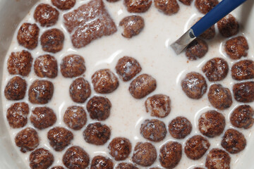 Breakfast cereal submerged in milk with a spoon ready to serve
