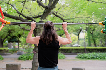 Man exercising on pull-up bar in outdoor park setting