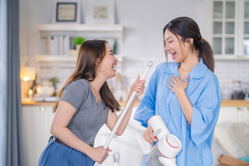 Obraz premium happiness love lgbtq stay home house cleaning tidy home day cheerful asian family hand hold cleaning tool singing song freshness laugh smile fun while house cleaning together