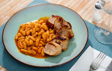 Tasty dish consisting in slices of roast pork on plate with beans