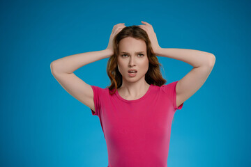 Woman expressing strong emotion while posing in a studio with a blue background during a creative...