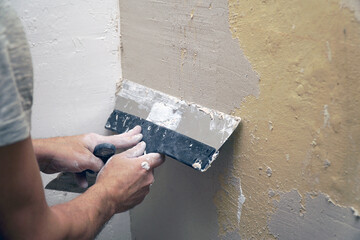 A man plastering a wall with a spatula