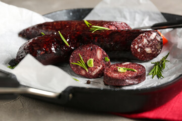 Frying pan with tasty blood sausage on grey background, closeup