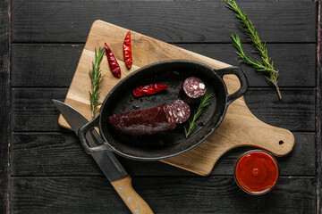 Composition with tasty blood sausage on dark wooden background, top view