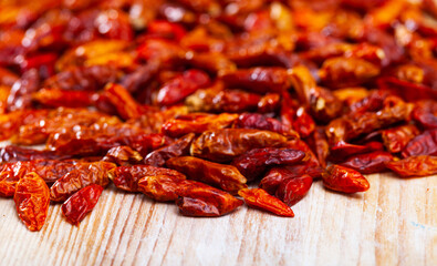 Pile of dried red cayenne peppers on wooden surface with place for text. Natural food background