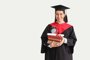 Female graduate with books and diploma on light background