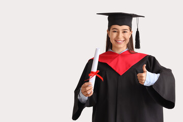 Female graduate with diploma showing thumb-up on light background