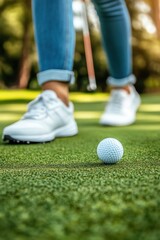 Golf ball on green with golfer preparing to putt low angle view on sunny day at course