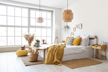 Interior of light bedroom with surfboard on bench and lamps