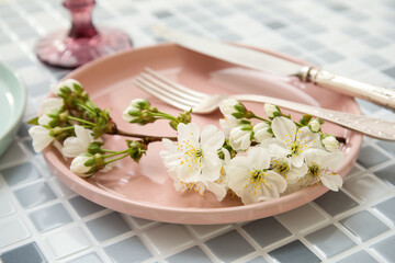Beautiful table setting with blooming branch on grey tile background, closeup