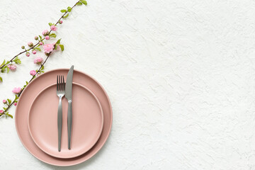 Beautiful table setting with pink blooming branches on white background