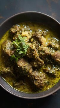 Delicious looking close up of Indian style palak gosht spinach meat dish with coriander garnish in a bowl against a dark background
