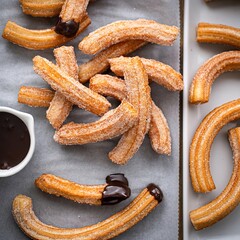Homemade churros with cinnamon sugar on parchment dipped into chocolate sauce