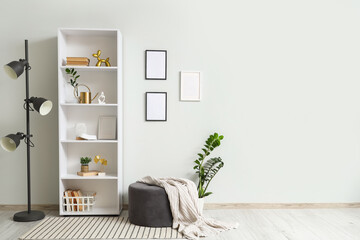 Interior of light room with shelf unit, lamp and pouf