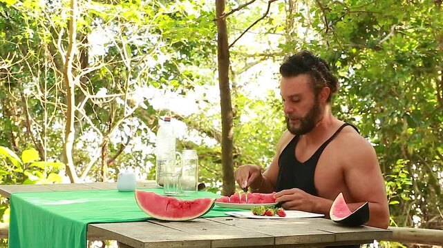 Man on picnic in park. Making and drinking watermelon juice.