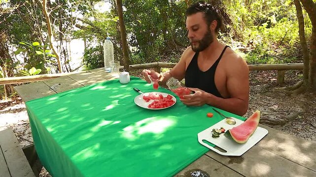 Man on picnic in park. Making and drinking watermelon juice.