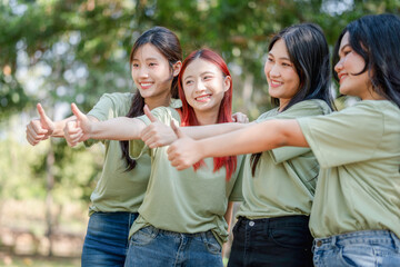 Group of cheerful volunteer Asian women showing thumbs up in a park
