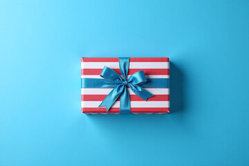 Fototapeta premium red and white striped gift box with a blue ribbon