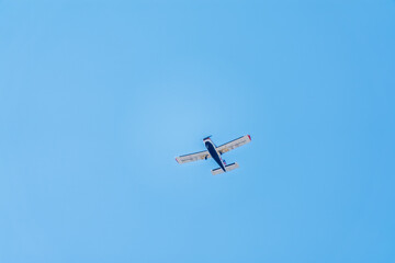 Small ultralight airplane with overhead wing and single propeller flying in sunset sky.