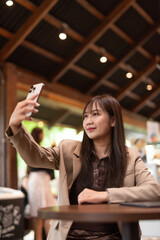 woman in cafe using mobile phone to take selfie picture