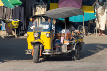 A traditional motor tricycle - tuk tuk leave a marketplace, Thailand