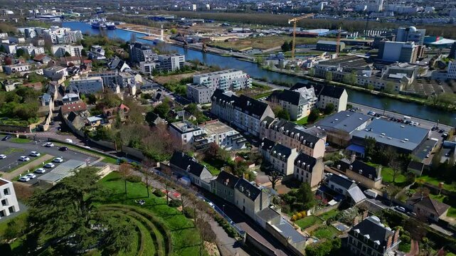 Caen, residential area, buildings along Canal de Caen &agrave; la Mer, and distant port and industrial zone, Normandy, France. Aerial drone forward