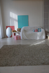 sofa with flower vases in the interior of a white room with a window