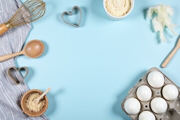 wooden rolling pin a wooden spoon a bowl of eggs a whisk and a heart shaped cookie cutter