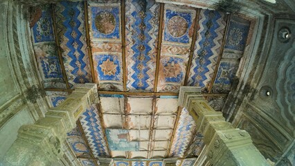 Weathered Painted Ceiling with Faded Blue Patterns and Columns Inside Historic Durga Temple,...