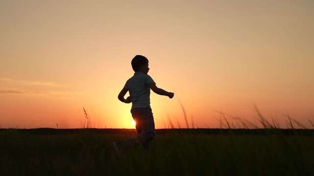Healthy lifestyle of boy. Boy boxer training punching kicking on meadow. Child boy karateka training in park, silhouette. Child boxer doing sports in park at sunset. Child kickboxer training outdoor