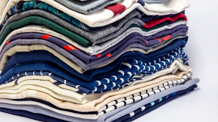 Stacked folded clothes, a neat pile of various colored shirts and textiles